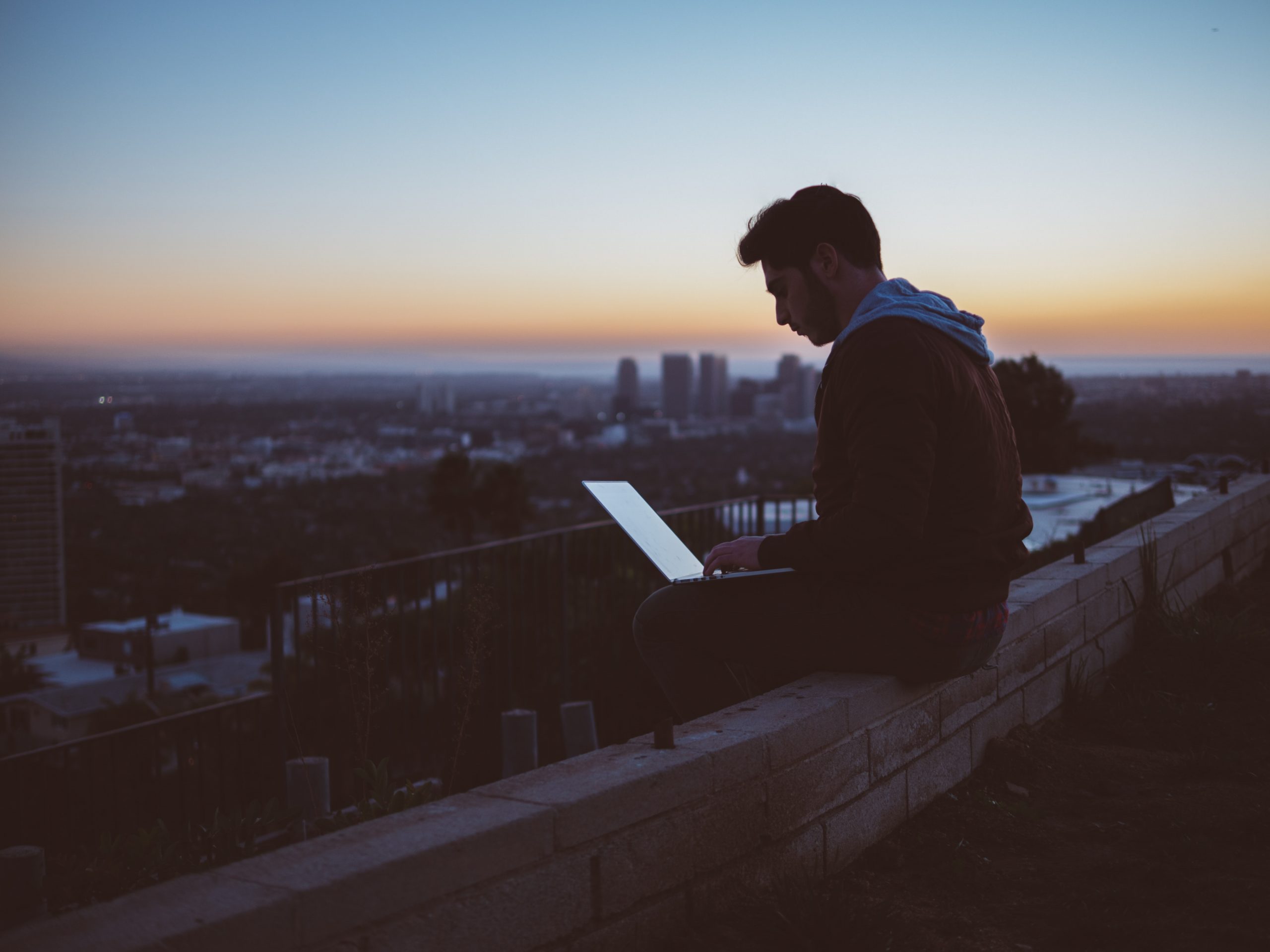 young man sitting on the top of the building with laptop