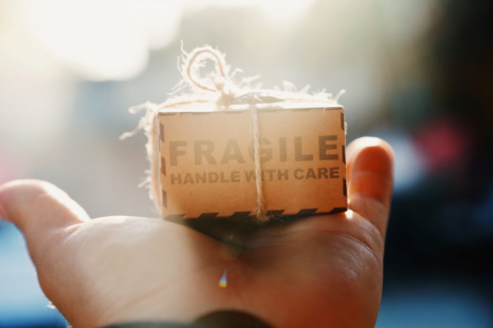 small cardboard box with fragile warning on top of a hand